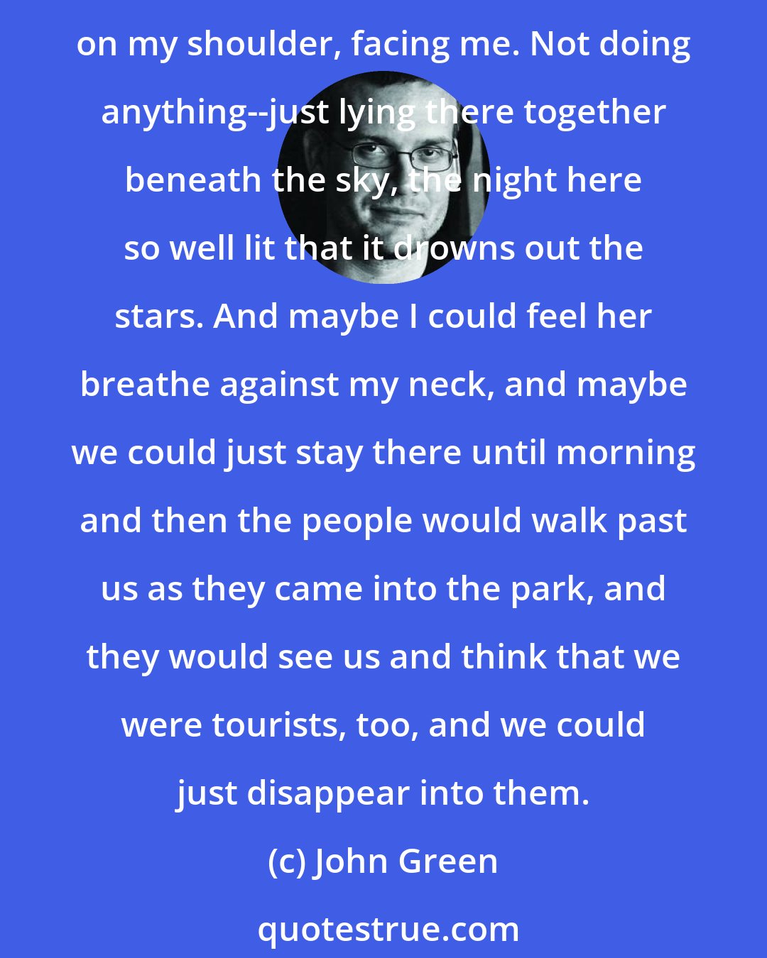 John Green: I felt tired for the first time, and I thought of us lying down on some grassy patch of SeaWorld together, me on my back and she on her side with her arm draped against me, her head on my shoulder, facing me. Not doing anything--just lying there together beneath the sky, the night here so well lit that it drowns out the stars. And maybe I could feel her breathe against my neck, and maybe we could just stay there until morning and then the people would walk past us as they came into the park, and they would see us and think that we were tourists, too, and we could just disappear into them.